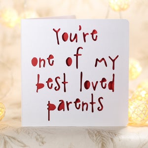 May include: A white card with the words "You're one of my best loved parents" written in red. The words are cut out of the card, creating a layered effect.