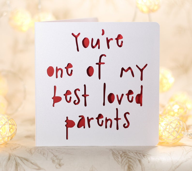 May include: A white card with the words "You're one of my best loved parents" written in red. The words are cut out of the card, creating a layered effect.