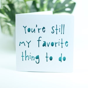 May include: White card with the text "You're still my favorite thing to do" written in teal blue.