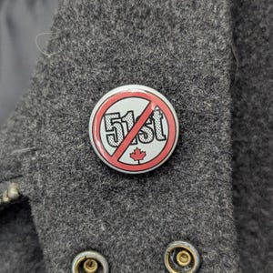 May include: A white button with a red circle and a diagonal red line through it. The text "51st" is inside the circle with a red maple leaf below it.