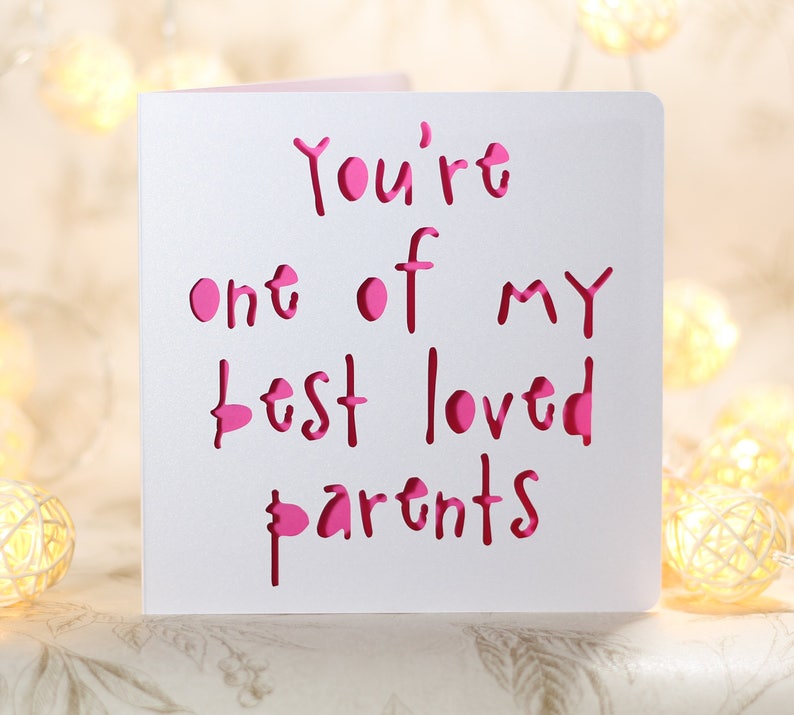 May include: White card with the words "You're one of my best loved parents" written in pink. The words are cut out of the card, creating a layered effect.