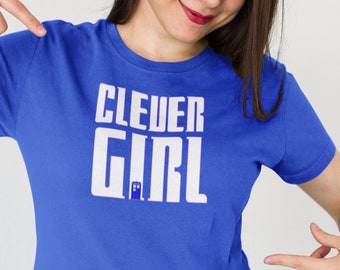 Puede incluir: Una camiseta azul real con texto blanco que dice "CLEVER GIRL" y un pequeño gráfico azul TARDIS.