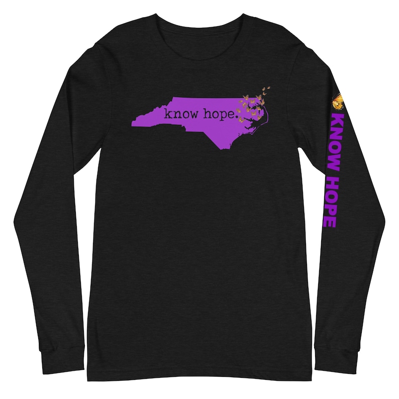 Peut inclure: T-shirt noir &agrave; manches longues avec un contour violet de la Caroline du Nord et les mots "know hope". La manche droite porte l'inscription "KNOW HOPE" en violet. Des papillons dor&eacute;s sont pr&egrave;s de la c&ocirc;te.