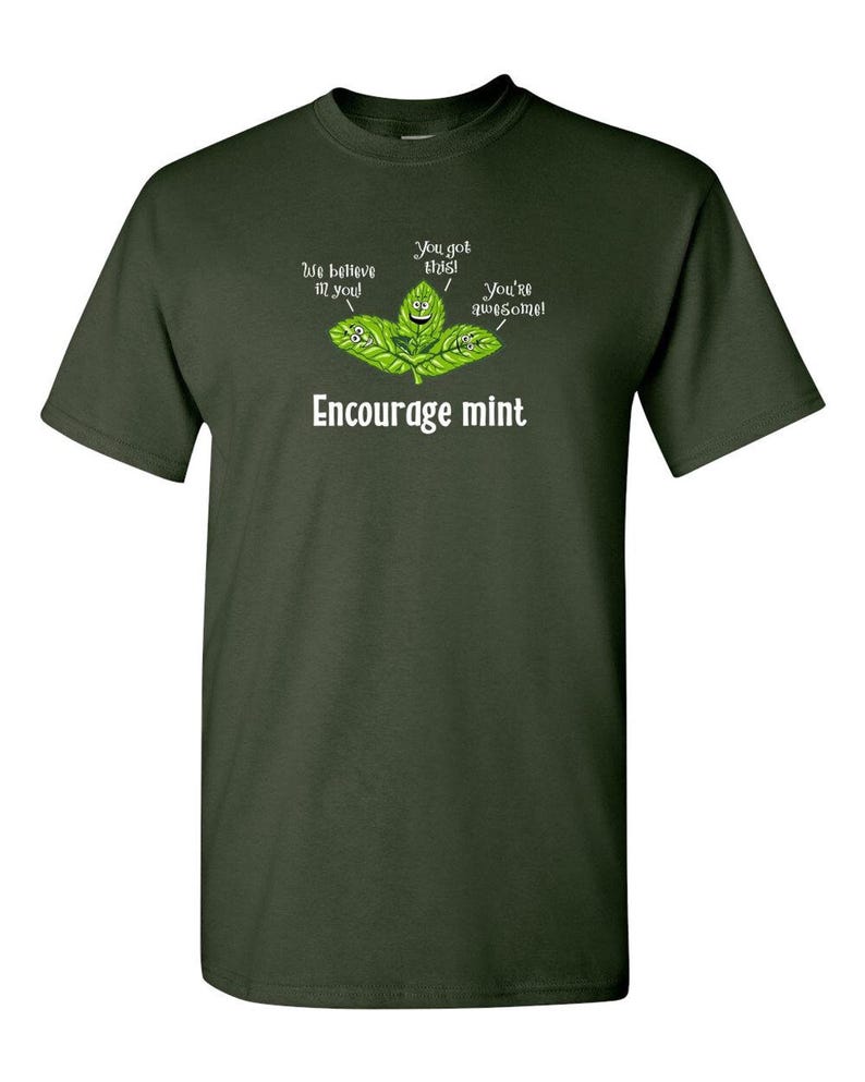 An olive green t-shirt printed with a graphic of smiling mint leaves and the text Encourage mint.