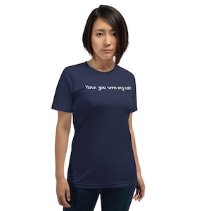 Pode incluir: Uma camiseta azul marinho com o texto "Have you seen my cat?" impresso em branco na frente.