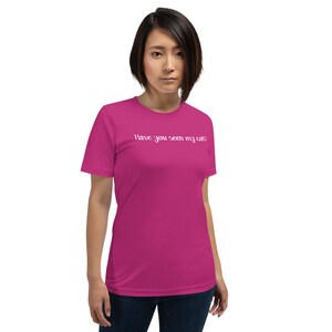 Pode incluir: Uma mulher vestindo uma camiseta rosa com o texto "Have you seen my cat?" impresso em branco.