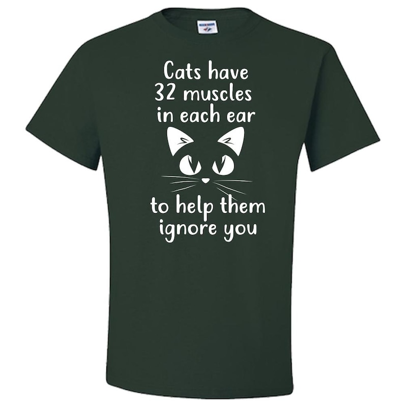 May include: A dark green t-shirt with a white graphic of a cat's face and the text "Cats have 32 muscles in each ear to help them ignore you."