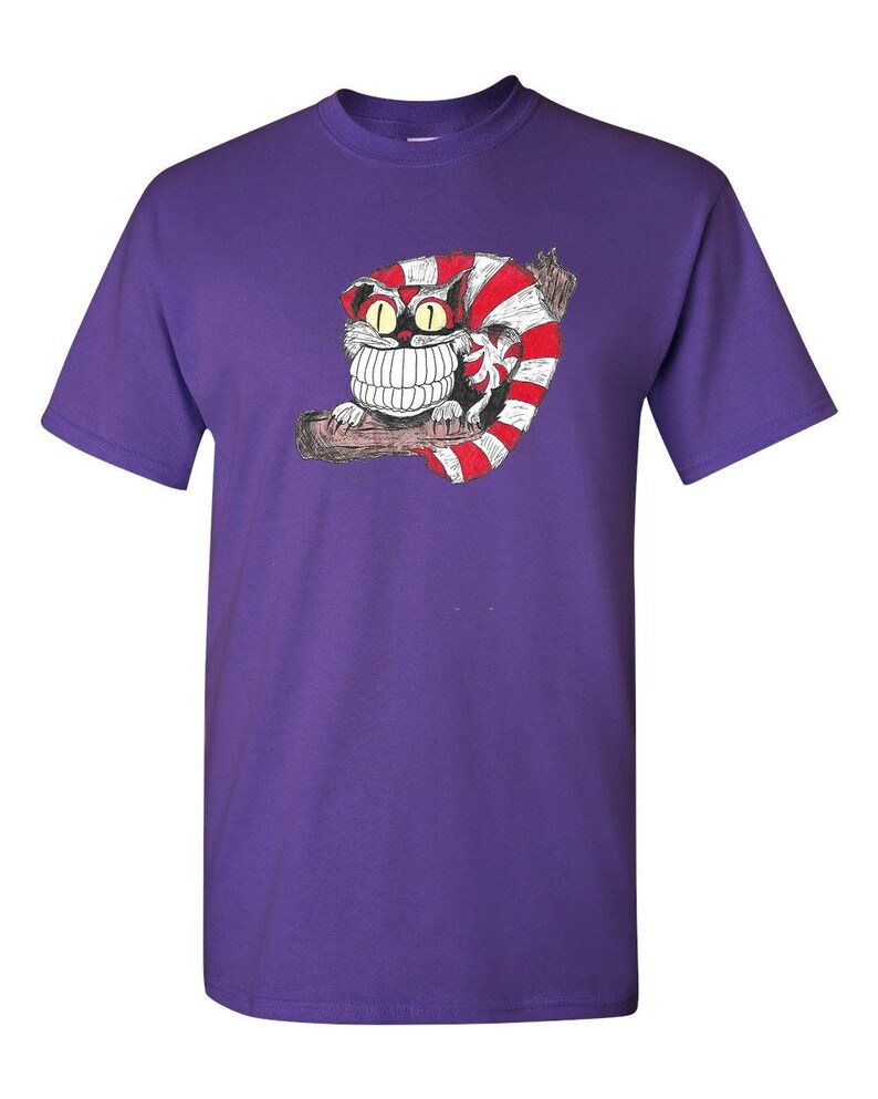 May include: Purple t-shirt with a cartoon Cheshire Cat from Alice in Wonderland. The cat is red and white with a large grin and big eyes.