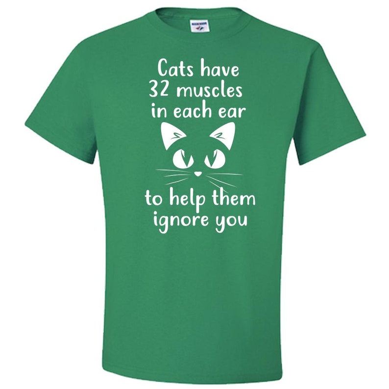 May include: Green t-shirt with a white cat face and the text "Cats have 32 muscles in each ear to help them ignore you."