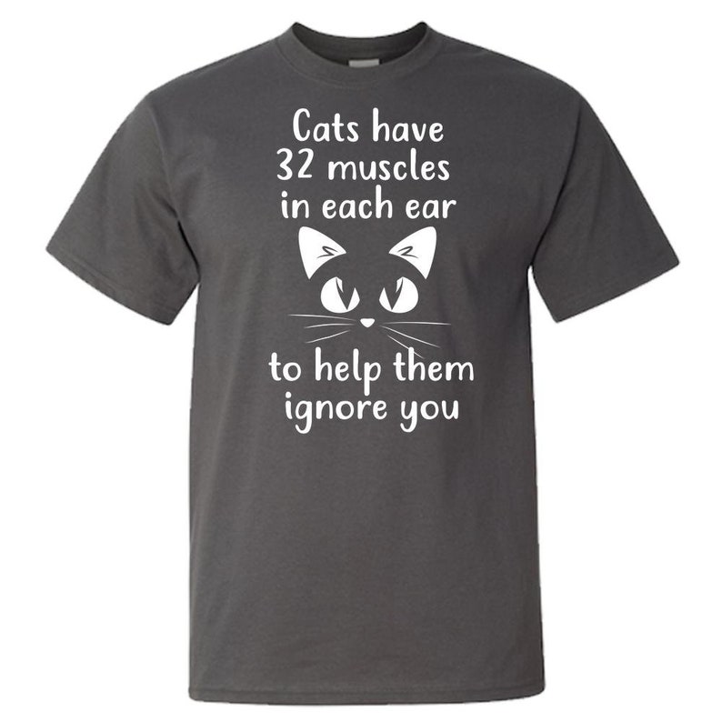 May include: Dark gray t-shirt with a white cat face and the text "Cats have 32 muscles in each ear to help them ignore you."
