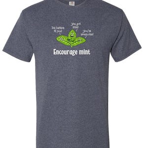 A dark heather gray t-shirt featuring a graphic of smiling mint leaves with the text Encourage mint.