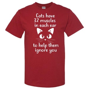 May include: Red t-shirt with a white cat illustration and the text "Cats have 32 muscles in each ear to help them ignore you."