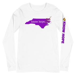 Peut inclure: T-shirt blanc &agrave; manches longues avec un contour violet de la Caroline du Nord et les mots "know hope." La manche droite affiche "KNOW HOPE" en violet. Un motif de papillon est sur la manche droite et le contour de la Caroline du Nord.