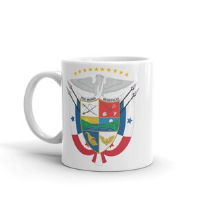 May include: White ceramic mug with a colorful image of the coat of arms of Panama. The coat of arms features a shield with a red, white, and blue design, a golden eagle, and the words "Pro Mundi" and "Beneficio".