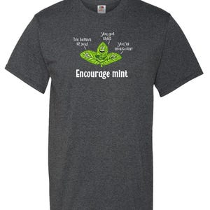 A dark charcoal gray t-shirt printed with a cartoon of smiling mint leaves and the text Encourage mint.