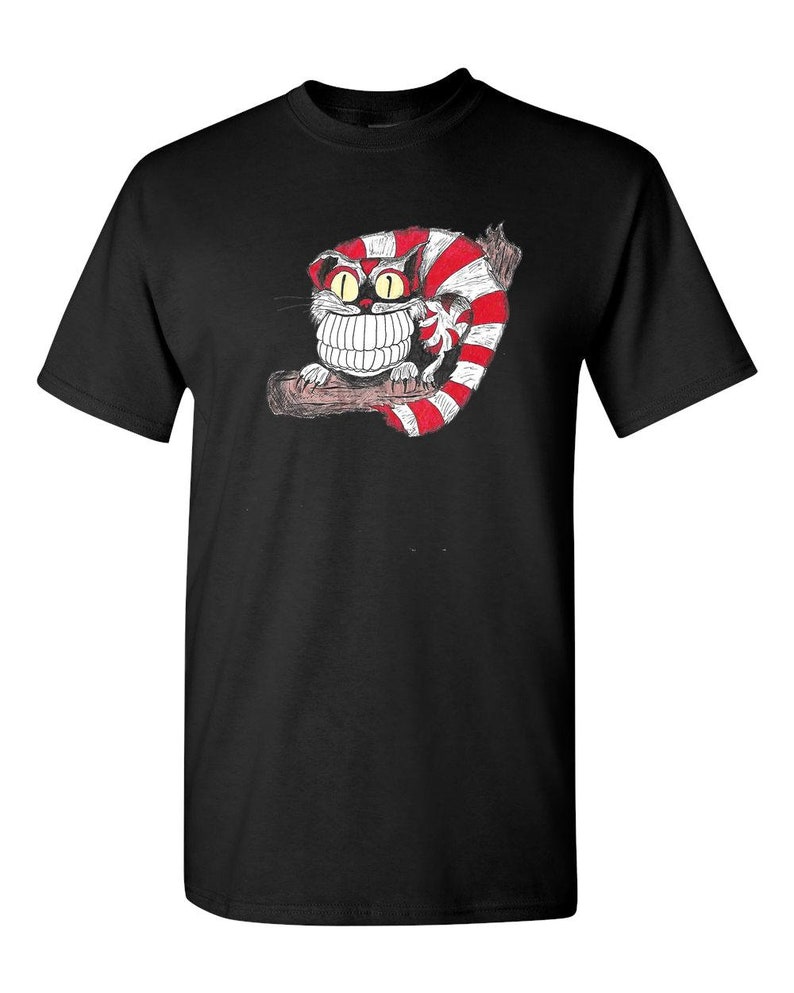 May include: Black t-shirt with a white and red striped Cheshire Cat illustration. The cat has a wide grin and large, yellow eyes.