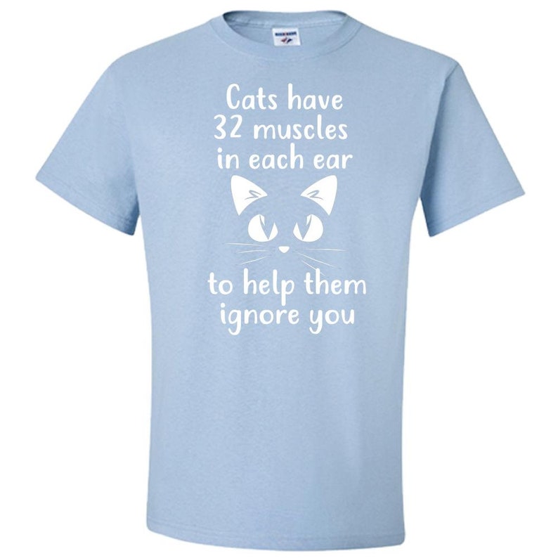 May include: Light blue t-shirt with a white cat face and the text "Cats have 32 muscles in each ear to help them ignore you."