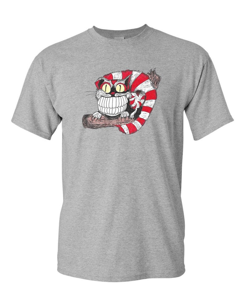May include: A gray t-shirt with a cartoon illustration of a Cheshire Cat with a wide grin and red and white stripes. The cat is sitting on a branch.