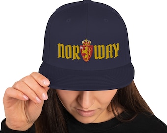 May include: A navy blue baseball cap with a gold embroidered lion and crown crest and the word "NORWAY" in gold lettering.