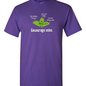 A purple t-shirt featuring a graphic of cartoon mint leaves and the text Encourage mint.