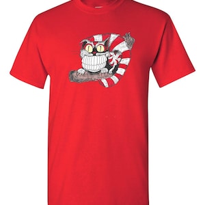 May include: Red t-shirt with a cartoon Cheshire Cat from Alice in Wonderland. The cat is grinning with large teeth and has red and white stripes.
