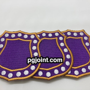 May include: Three purple and gold embroidered patches with white dots around the edges. The patches are shaped like shields and have a website address, "pgjoint.com", printed in the center.