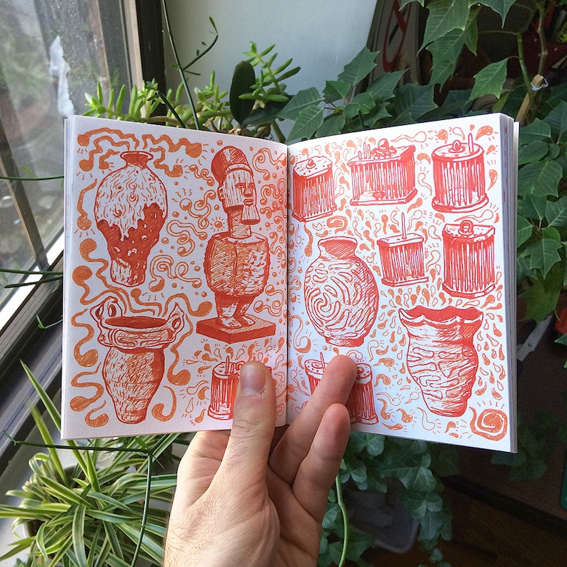 May include: Open sketchbook with orange ink illustrations of various vases, statues, and cylindrical objects. The drawings are detailed and set against a backdrop of swirling patterns. The sketchbook is held open by a hand, showcasing the artwork.
