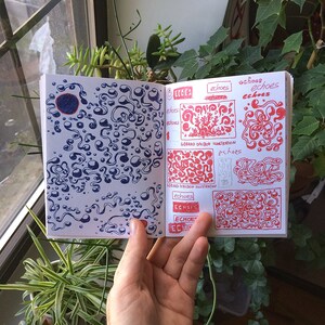 May include: Open sketchbook with blue and red ink illustrations. The left page features a blue abstract design with a dark blue circle. The right page displays red illustrations with the word "echoes" and "GERARD DALBON ILLUSTRATION".