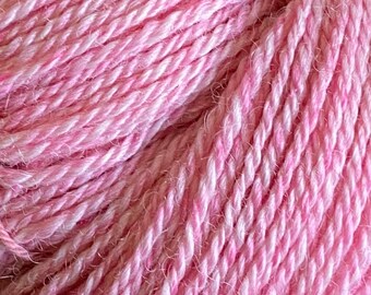 Könnte beinhalten: Nahaufnahme eines rosafarbenen Garnknäuels. Das Garn ist weich und flauschig mit einem dezenten Glanz.
