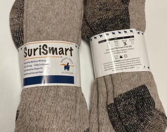 Könnte beinhalten: Zwei Paar SuriSmart Alpaka-Fasersocken. Ein Paar ist einfarbig beige, das andere ist beige mit braunen und schwarzen Akzenten. Die Socken haben verstärkte Zehen und Fersen und sind vollständig gepolstert.