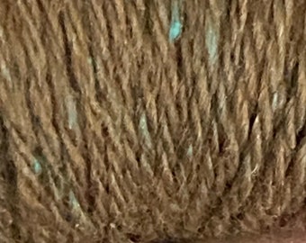Könnte beinhalten: Nahaufnahme eines braunen Garnknäuels mit hellblauen Flecken.