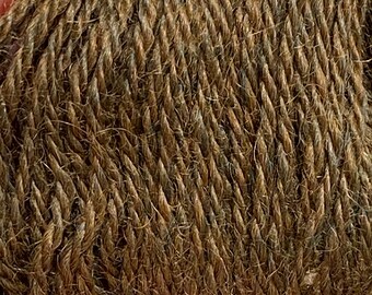 Könnte beinhalten: Nahaufnahme eines Knäuels brauner Wolle mit texturierter, gedrehter Optik. Das Garn hat eine Mischung aus hellen und dunklen Brauntönen mit dezenten blauen Akzenten. Die Fasern sind eng gewickelt und erzeugen eine dichte, strapazierfähige Textur. Ideal für Strick- und Häkelprojekte.