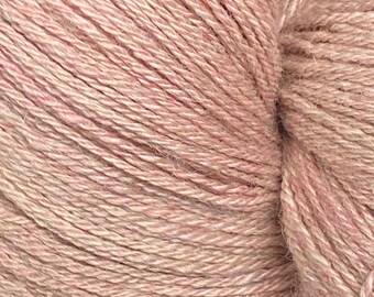 Könnte beinhalten: Nahaufnahme eines Garnknäuels in einem weichen, gedämpften Rosa. Das Garn scheint eine Naturfaser zu sein, mit einer leicht strukturierten Oberfläche. Die Stränge sind eng gewickelt und bilden eine dichte, kompakte Form, ideal für Strick- oder Häkelprojekte.