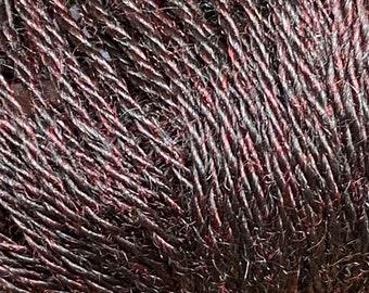 Könnte beinhalten: Nahaufnahme eines Knäuels dunkelbraunen Garns mit einem dezenten roten Schimmer. Das Garn besteht aus einer weichen, natürlichen Faser und hat eine leicht strukturierte Oberfläche.