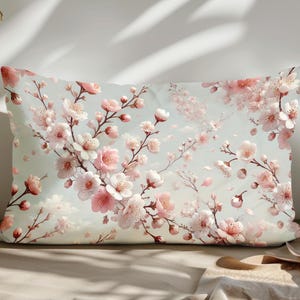May include: A rectangular pillow with a floral pattern of pink and white cherry blossoms on a light blue background.