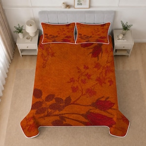 Può includere: Un set da letto composto da una trapunta e due federe abbinate con uno sfondo arancione vivace e un motivo floreale di rose rosso scuro. La trapunta e le federe sono rifinite con un bordo bianco profilato che crea un contorno netto.