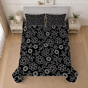 May include: A black bedspread and two matching pillow shams featuring a white dotted floral pattern. The bedding set displays a repeating design of stylized flowers and leaves created with small white dots against a solid black background.