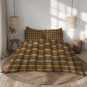 Op de afbeelding: Een bruine beddengoedset met bloemenpatroon met een herhalend ontwerp van oranje en blauwe bloemen. De set bevat een dekbedovertrek en twee kussenslopen. Het beddengoed wordt gepresenteerd op een bed met een houten hoofdbord.