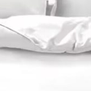 a bed with a white comforter and pillows