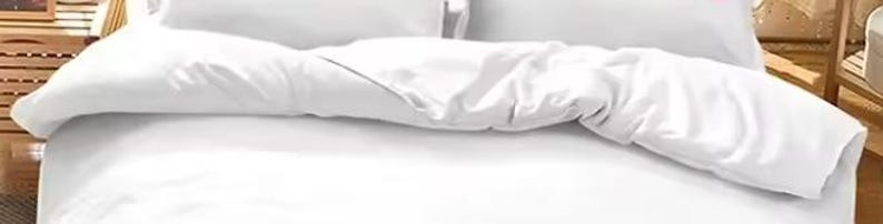 a bed with a white comforter and pillows