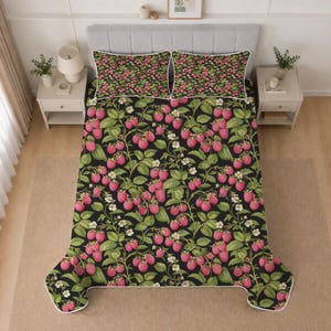Könnte beinhalten: Ein Bettwäscheset bestehend aus einer Steppdecke und zwei Kissenbezügen mit schwarzem Hintergrund und einem wiederkehrenden Muster aus rosa Himbeeren, grünen Blättern und kleinen weißen Blüten. Die Decke und Bezüge haben eine weiße Paspelierung.