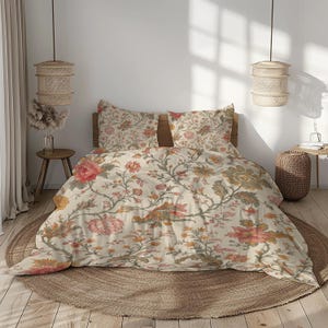 May include: A cream-coloured floral bedding set with large pink, orange, and green flowers and foliage. The set includes a duvet cover and two pillowcases, displayed on a wooden bed frame. The bed is set on a round, woven rug.
