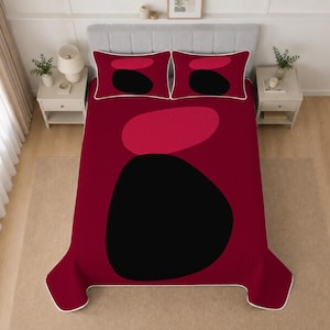 May include: A bedding set featuring a deep red quilt and two matching pillow shams. The design displays large, abstract, rounded shapes in solid black and a lighter shade of red, with a thin white border outlining the edges of the quilt and shams.