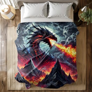 Könnte beinhalten: Eine schwarze und rote Drachendecke mit einem feurigen Design. Der Drache speit Feuer über eine Bergkette. Die Decke liegt auf einem Bett mit weißen Kissen und einem Nachttisch aus Holz.