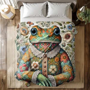 Puede incluir: Una colcha con un diseño de rana colorida. La rana tiene grandes ojos azules y viste un atuendo con estampado floral y cuello de encaje. La colcha presenta un fondo crema con motivos florales y mariposas.