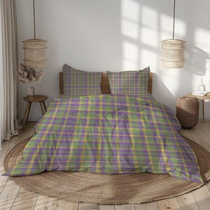 May include: A bed dressed with a duvet cover and two pillowcases. The bedding displays a plaid pattern in purple, green, and yellow. The bed is set against a neutral-toned wall. The room is lit by natural light.
