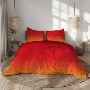 Peut inclure: Un lit avec une housse de couette dégradée rouge à orange et deux taies d'oreiller assorties. La literie est sur un cadre de lit en bois, avec un tapis rond tissé en dessous. La pièce a une palette de couleurs neutres avec de la lumière naturelle.