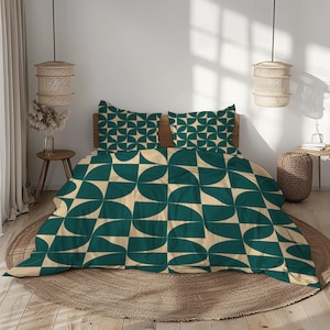 Op de afbeelding: Een beddengoedset met een dekbedovertrek en twee kussenslopen. Het beddengoed heeft een geometrisch patroon in teal en crème. Het ontwerp bestaat uit halve cirkels gerangschikt in een raster. Het bed staat op een ronde, geweven vloerkleed.