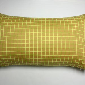 以下が含まれることがあります： マスタードイエローの背景にネオングリーンの格子模様が施された長方形の枕。 枕は装飾品で、おそらくベッドやソファ用で、部屋に色と幾何学的なデザインを加えます。
