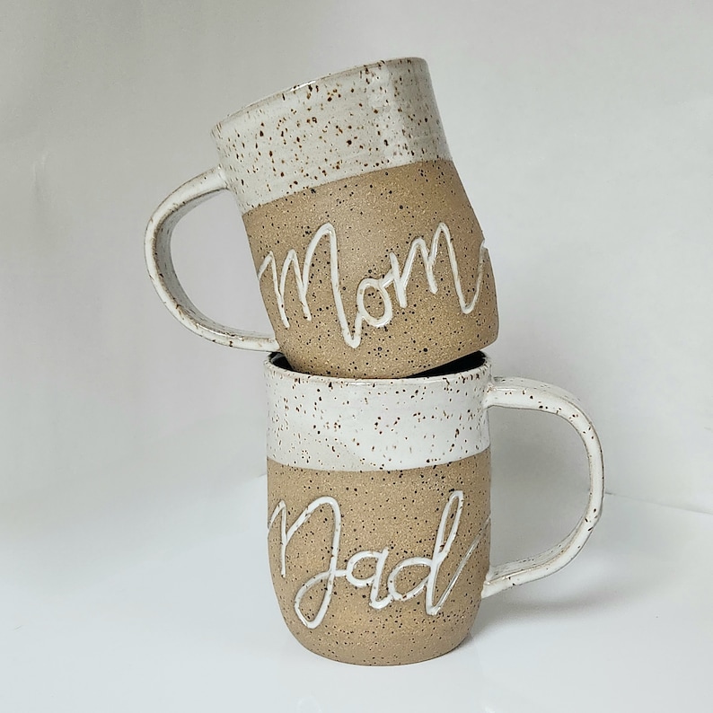 Mugs made out of speckled brownstone clay and glazed with white on the top half, interior, and handle.  Glaze on the interiors allows for easy clean up of coffee or tea stains.